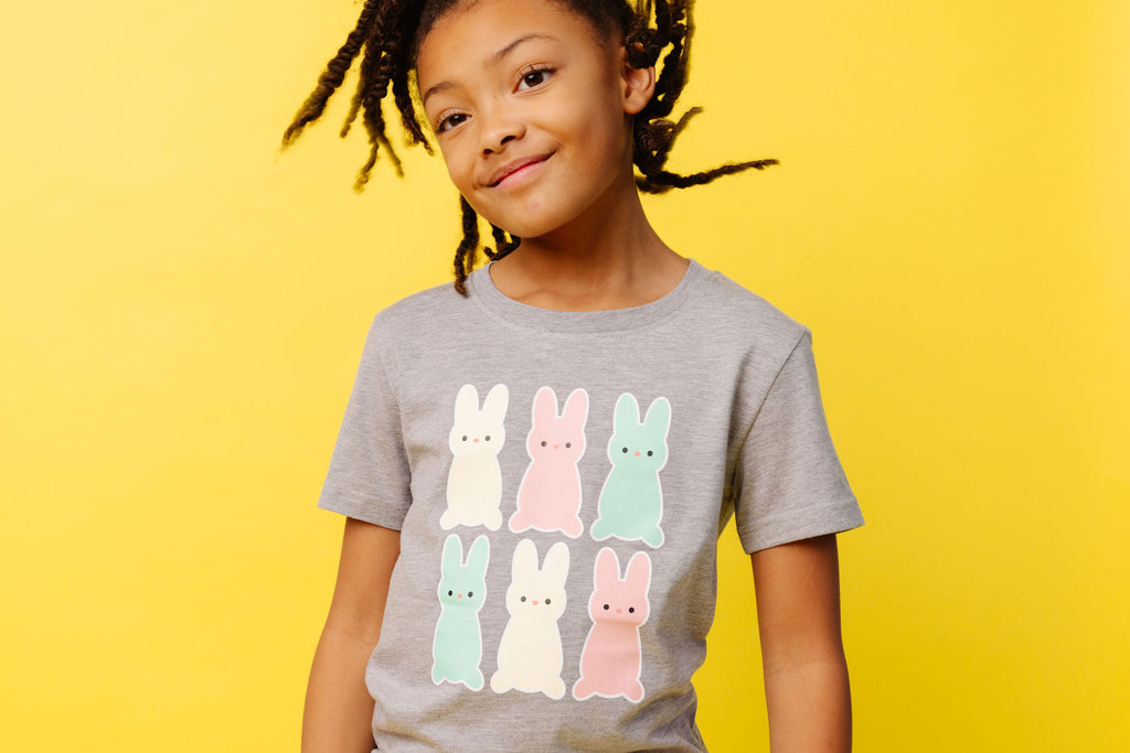 Child wears grey t-shirt with 6 pastel coloured marhsmallow bunnies for easter