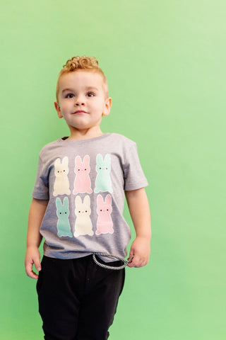 Child wears grey t-shirt with 6 pastel coloured marhsmallow bunnies for easter